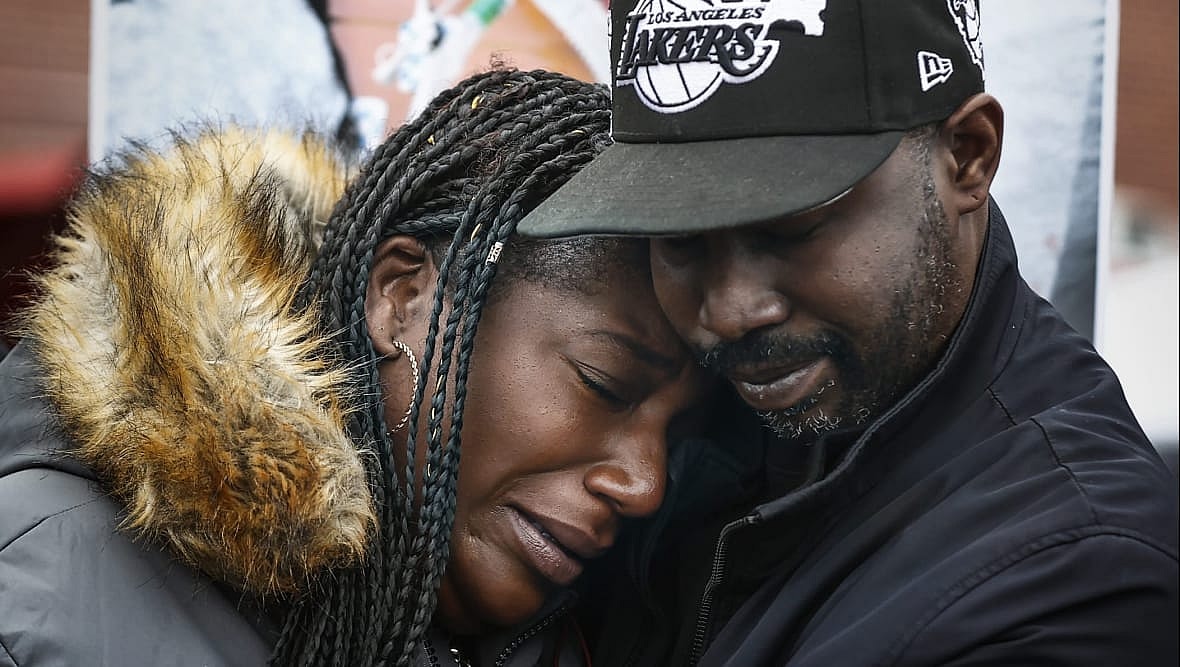Kenyana Dixon, sister of Tyre Nichols, is hugged by a man in a black Lakers baseball cap