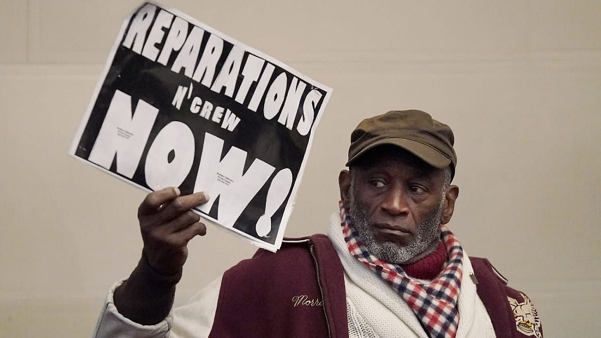 Morris Griffin holds up a sign for reparations