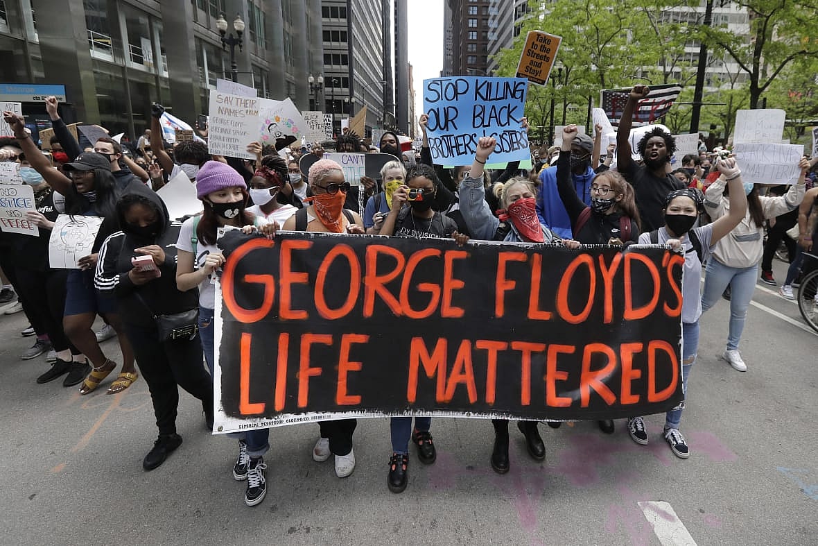 Protesters hold signs as they march during a protest over the death of George Floyd