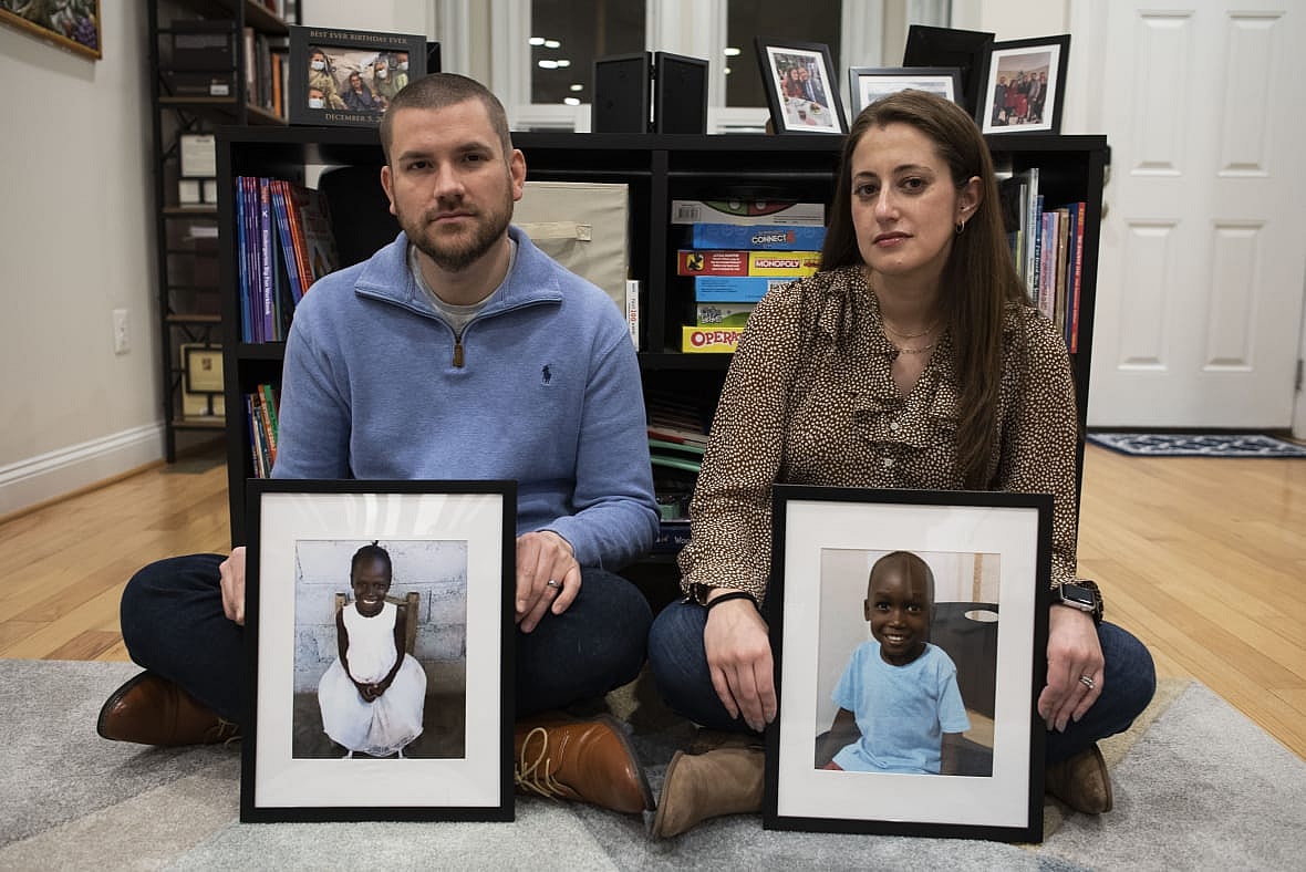 Bryan and Julie Hanlon hold photos of their adopted Haitian children, Gina and Peterson