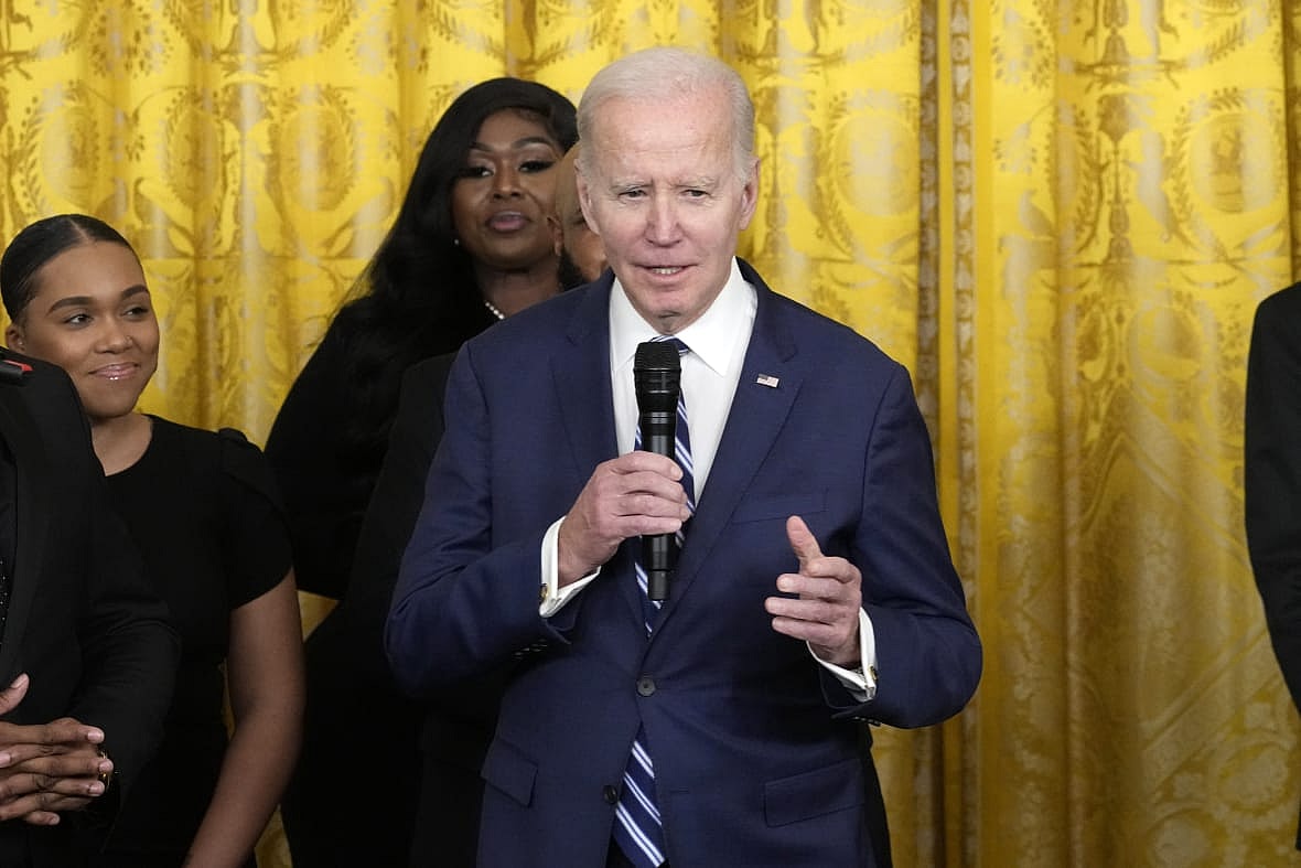 President Joe Biden holding a microphone wearing a blue jacket and blue-striped tie