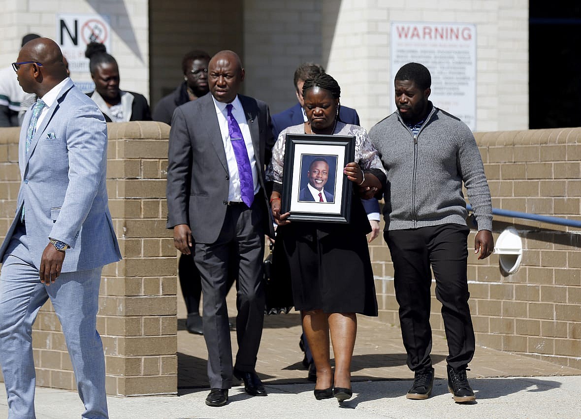 Attorney Ben Crump with Caroline Ouko, holding a portrait of her son Irvo Otieno, and her older son Leon Ochieng