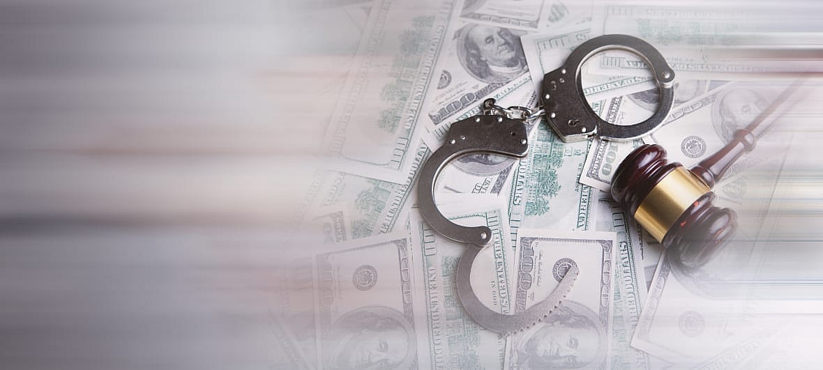 Handcuffs and a gavel on a pile of $100 bills