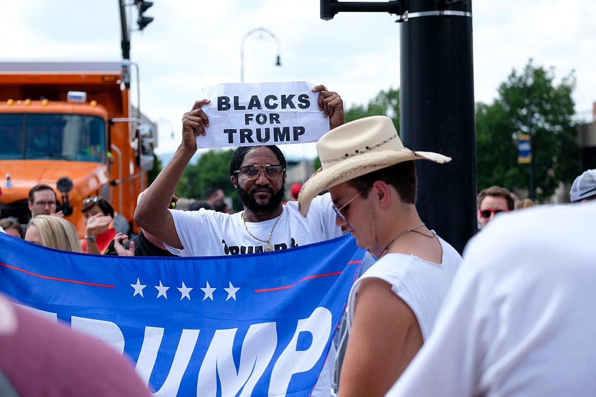 A man holds a "Blacks for Trump" sign