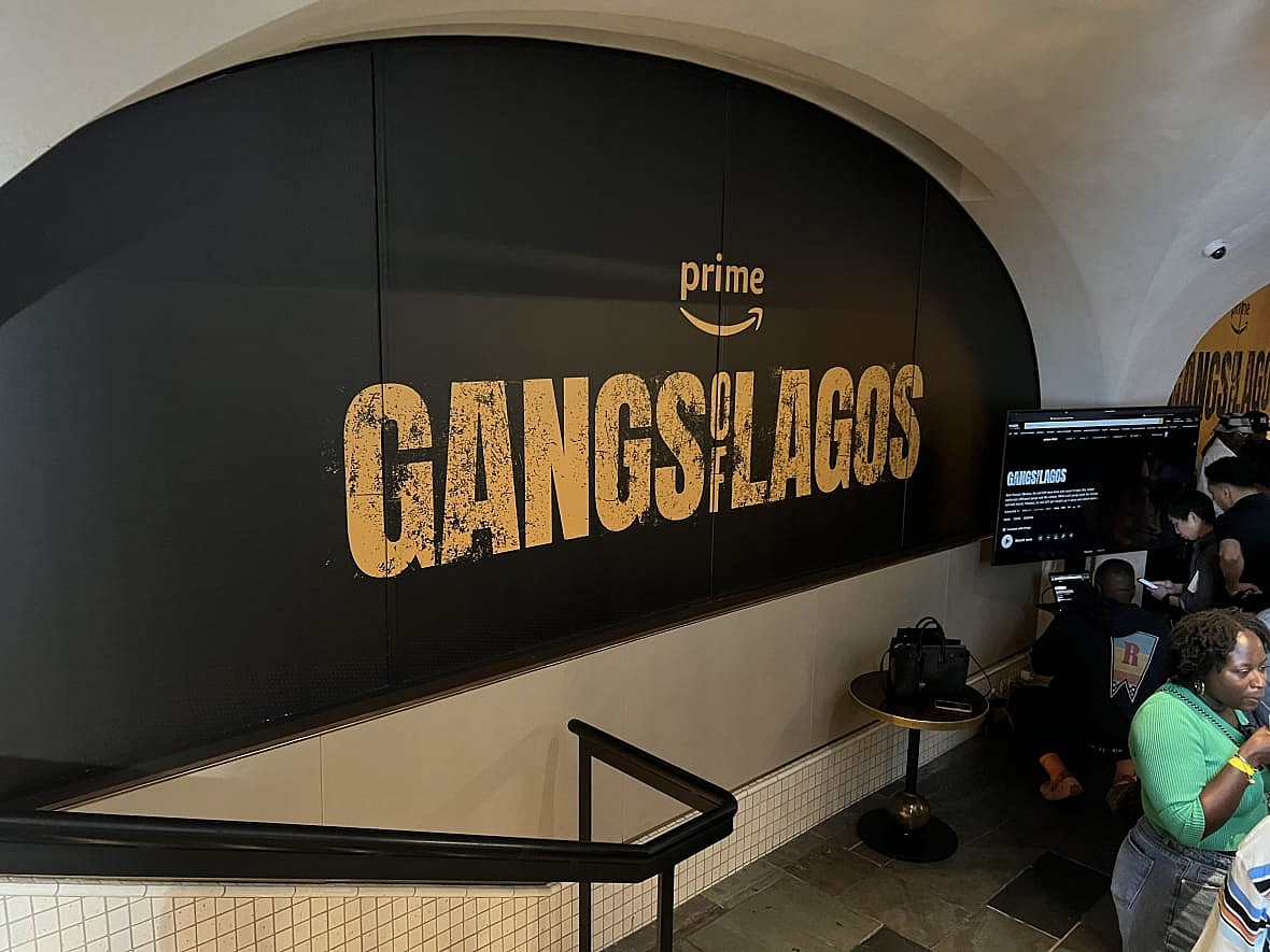 Large black sign with gold letters reading "Gangs of Lagos"