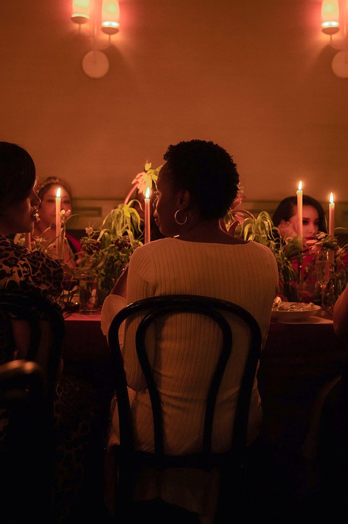 Women sit around a table lighted by candles