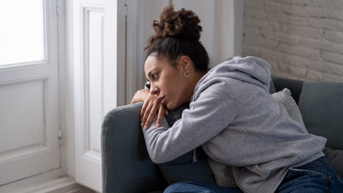 A woman lays despondently on a couch