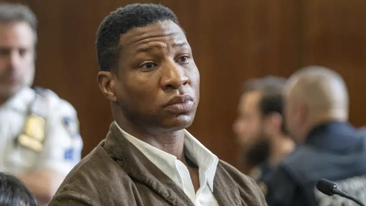 Actor Jonathan Majors wearing a brown jacket and white shirt