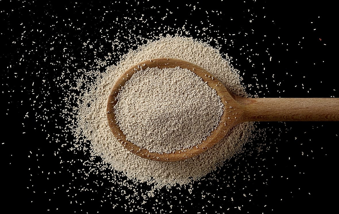 A wooden spoon overflowing with yeast