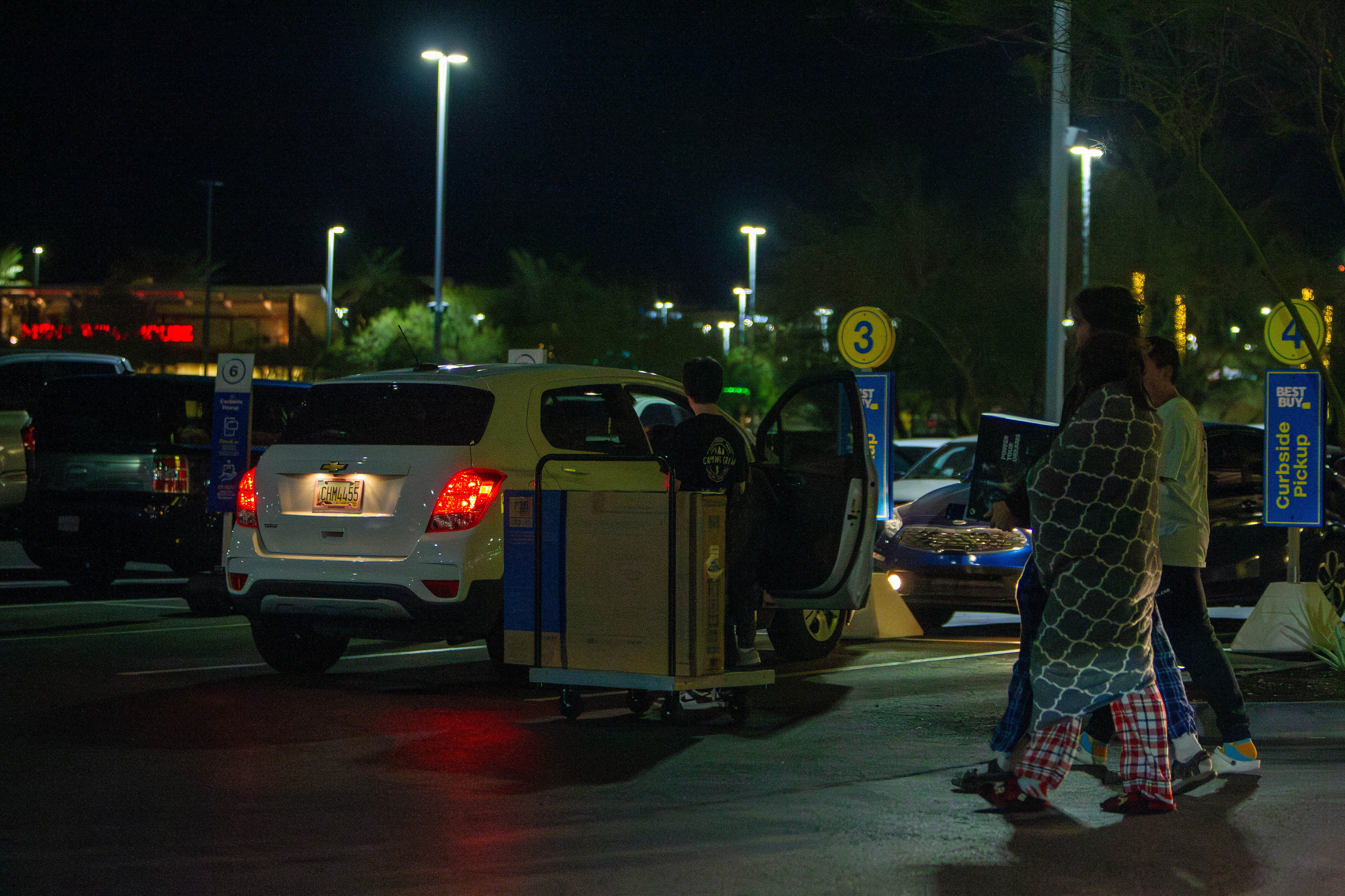 A Best Buy employee helps load a TV into a customer’s car