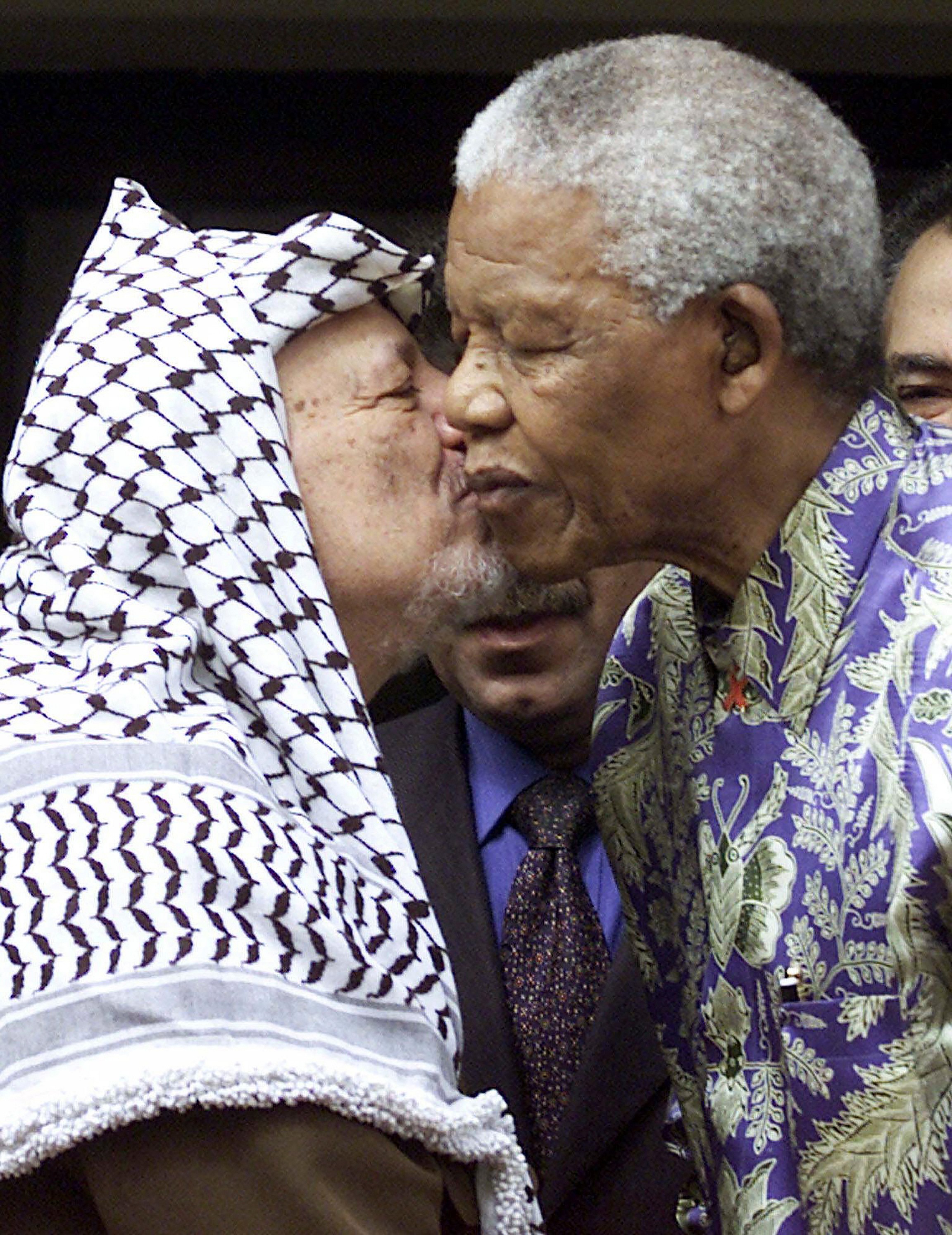 Late Palestinian leader Yasser Arafat embraces the late former South Africa President Nelson Mandela