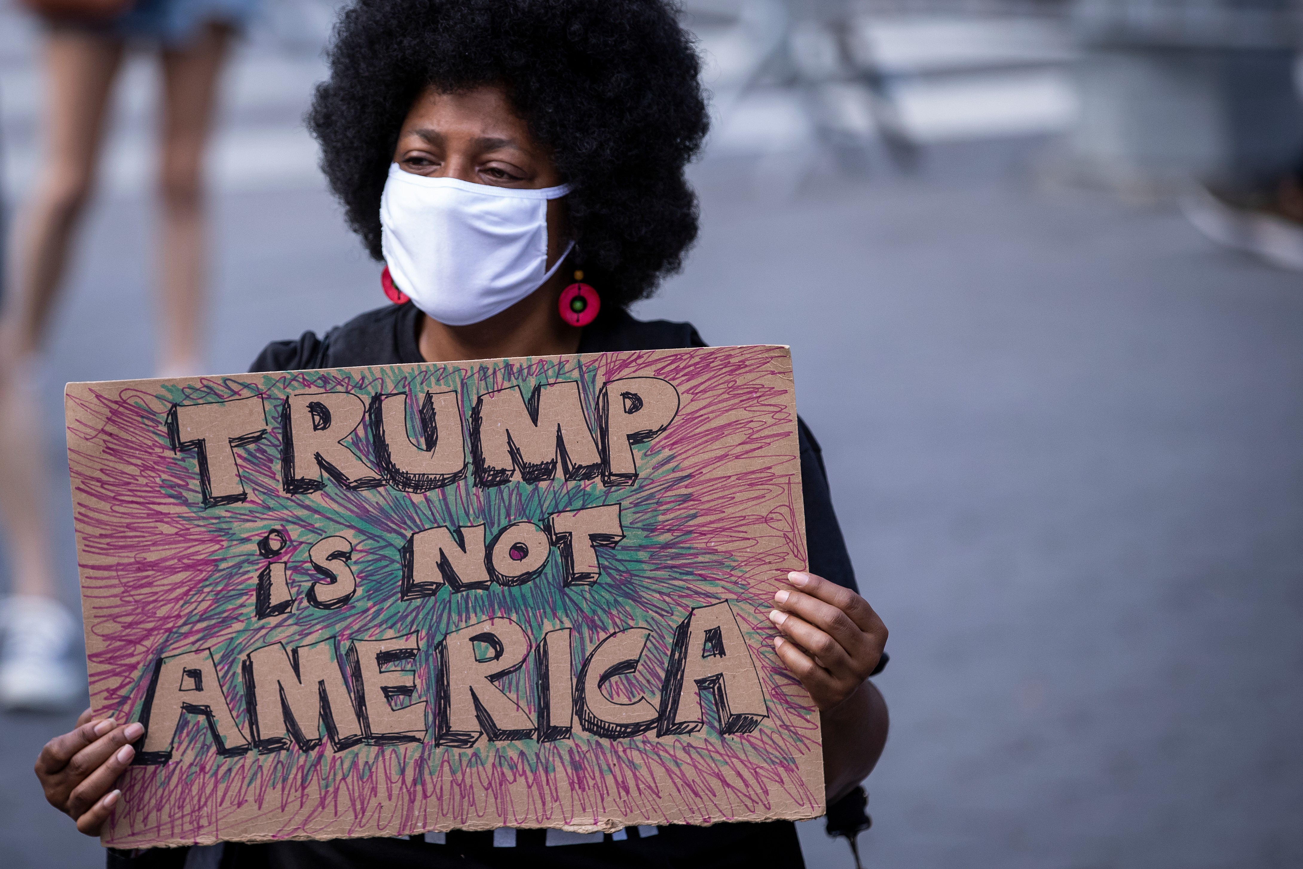A protester holds a homemade sign that says, “Trump is Not America”