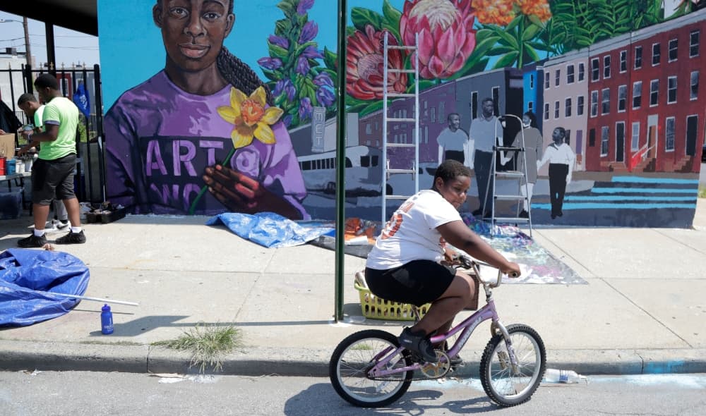 A boy rides his bicycle after volunteering to paint a mural outside the New Song Community Church in the Sandtown section of Baltimore. In the latest rhetorical shot at lawmakers of color, President Donald Trump over the weekend vilified Cummings' majority-black Baltimore district as a "disgusting, rat and rodent infested mess" where "no human being would want to live." (AP Photo/Julio Cortez)