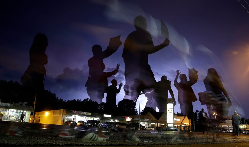 In this Aug. 20, 2014, file photo, protesters march in the street as lightning flashes in the distance in Ferguson, Mo. Michael Brown's death on Aug. 9, 2014, at the hands of a white Missouri police officer stands as a seismic moment of race relations in America. The fledgling Black Lives Matter movement found its voice, police departments fell under intense scrutiny, progressive prosecutors were elected and court policies revised. (AP Photo/Jeff Roberson, File)