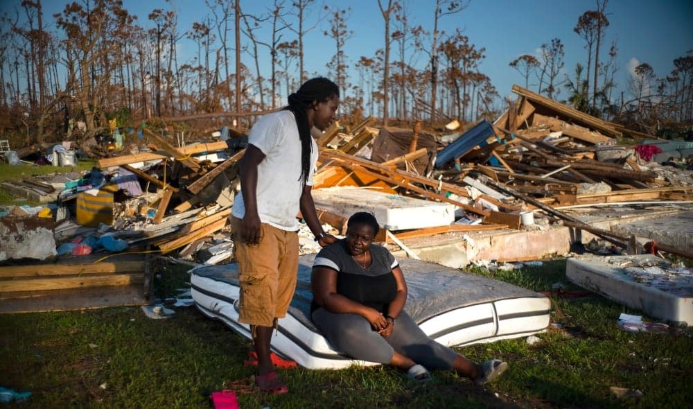 Synobia Reckley pauses on a wet mattress as her husband Dexter Edwards consoles her amid the remains of their home destroyed by Hurricane Dorian in Rocky Creek East End, Grand Bahama, Bahamas, Sunday, Sept. 8, 2019. The couple married two days after Hurricane Mathew hit in 2016 but did not do serious damage. (AP Photo/Ramon Espinosa) thegrio.com