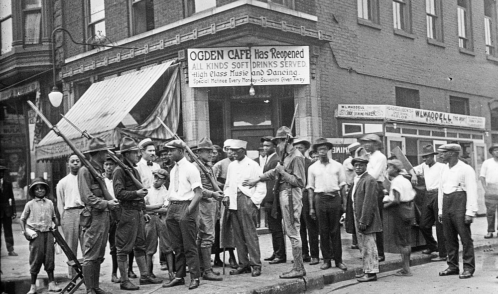 Crowd of men and armed National Guard in front of the Ogden Cafe during the race riots in Chicago, Illinois, 1919.