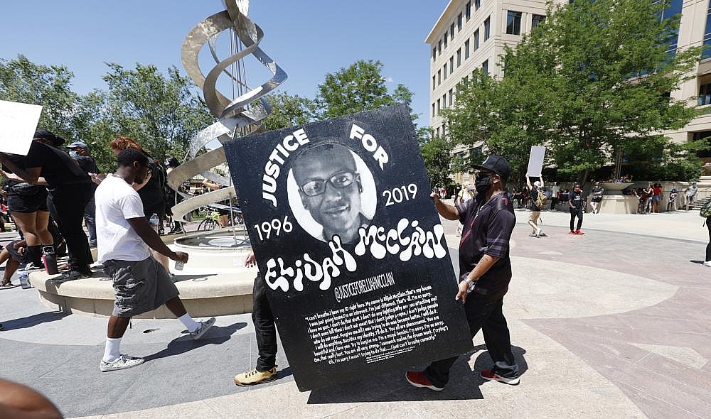 Demonstrators carry a giant placard during a rally and march over the death of Elijah McClain