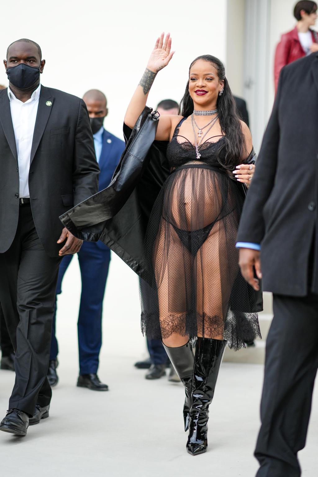Singer and actor Rihanna waves, wearing a black net skirt trimmed in lace with a black bra and g-string