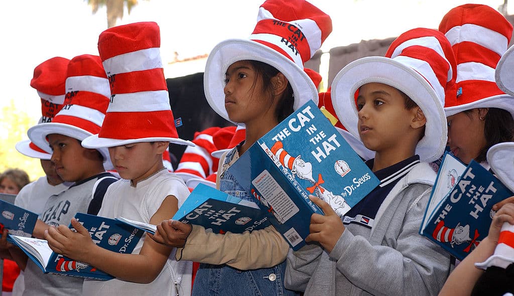 Children read from "The Cat in the Hat" book at a ceremony honoring the late children's book author Dr. Seuss (Theodore Geisel) with a star on the Hollywood Walk of Fame on March 11, 2004 in Hollywood , California. (Photo by Vince Bucci/Getty Images) thegrio.com