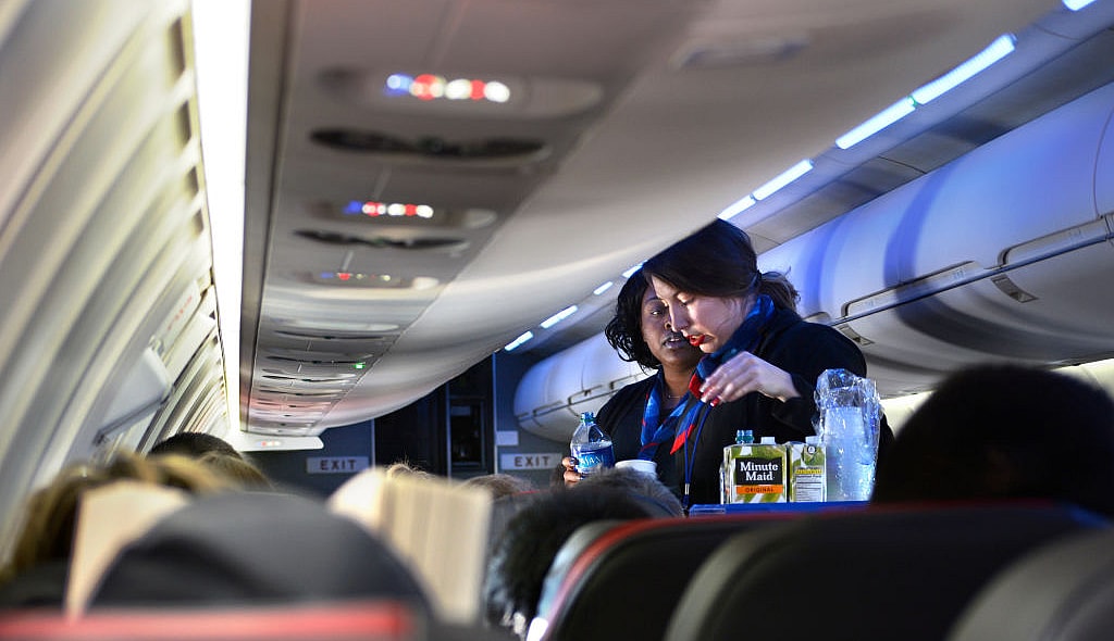 DALLAS, TEXAS - DECEMBER 12, 2018: Two American Airlines flight attendants serve drinks to passengers after departing Dallas/Fort Worth International Airport. (Photo by Robert Alexander/Getty Images) thegrio.com