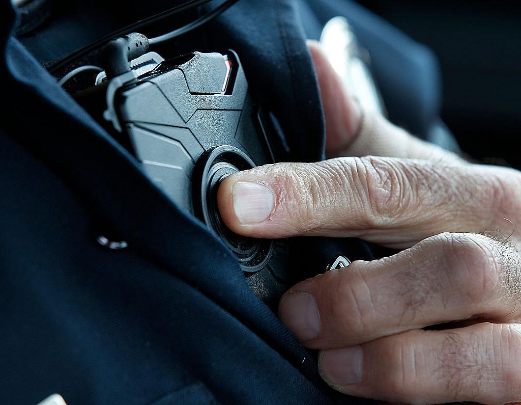 A patrol officer presses a button to start a new body camera recording