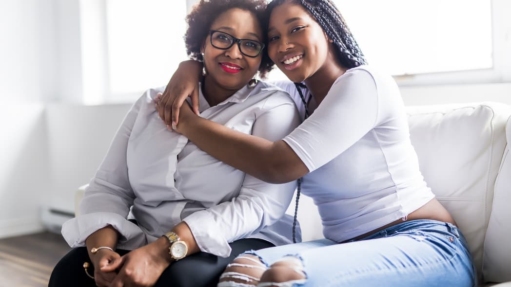 A affectionate mother and daughter sitting on a sofa