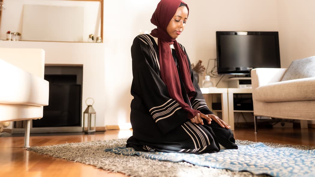 A Muslim woman kneels to pray