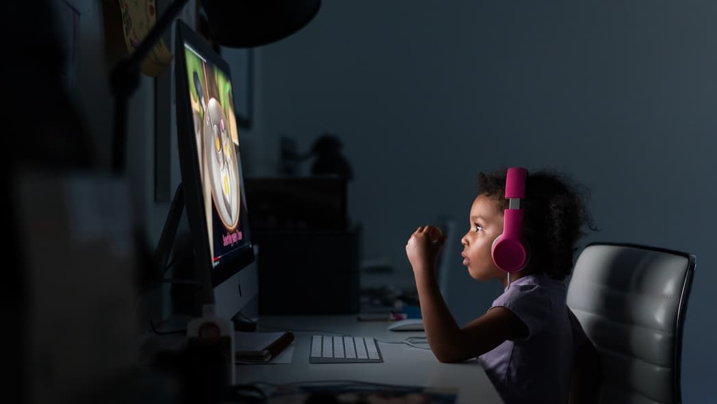 A child wearing headphones looks at a computer screen