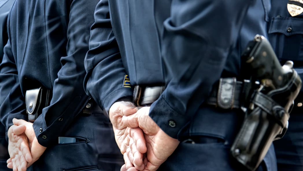 Police officers with their hands behind their backs