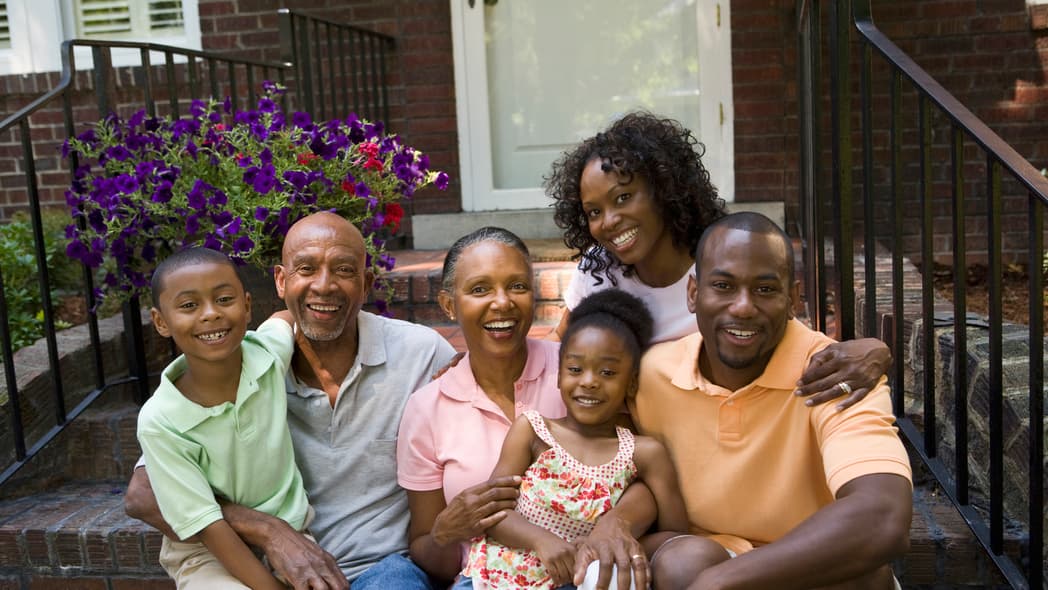 A family sits on the steps of a house