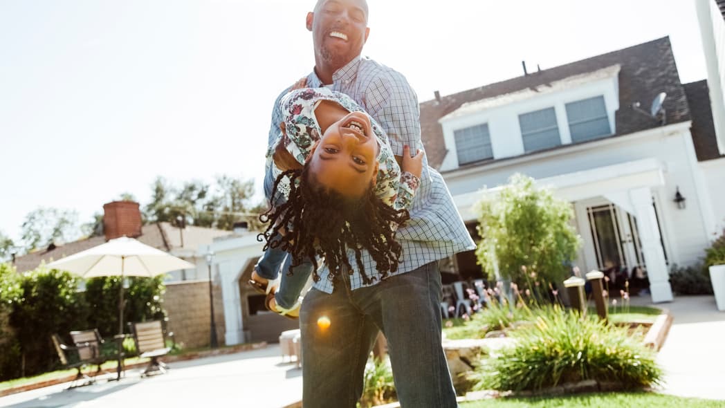 A man holds a young girl as she leans backwards