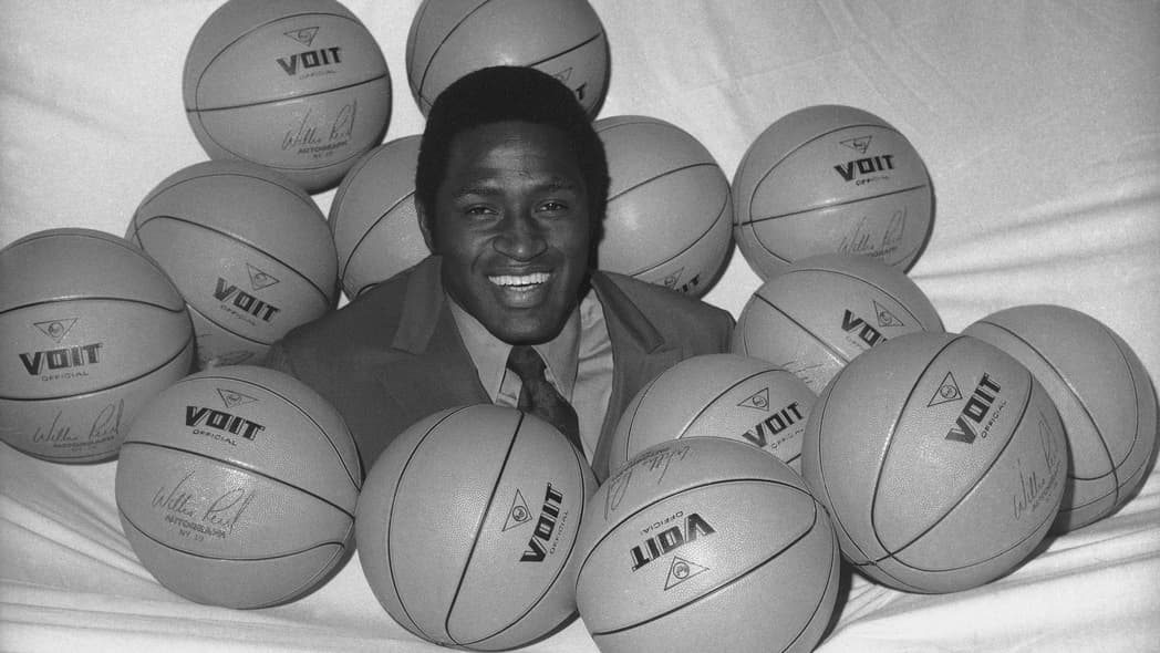 Black-and-white photo of New York Knicks NBA player Willis Reed surrounded by basketballs