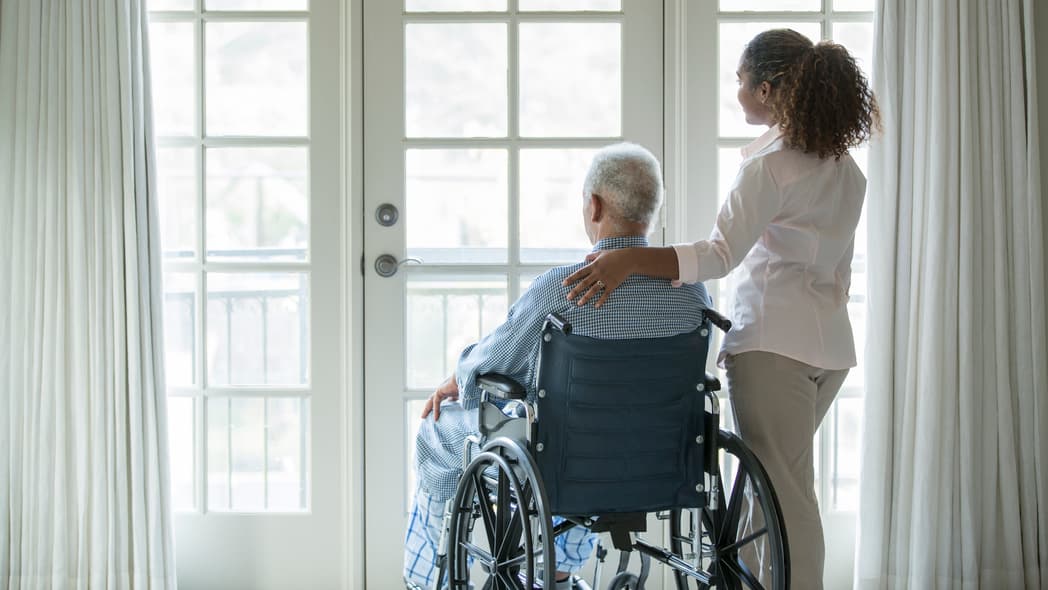 A woman stands beside a man in a wheelchair