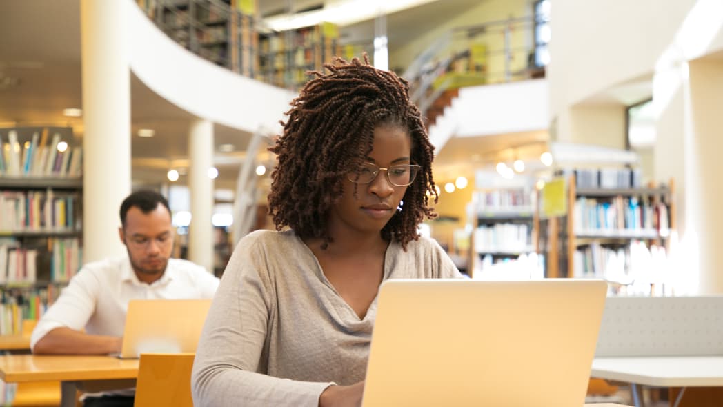 A woman uses a laptop in a library