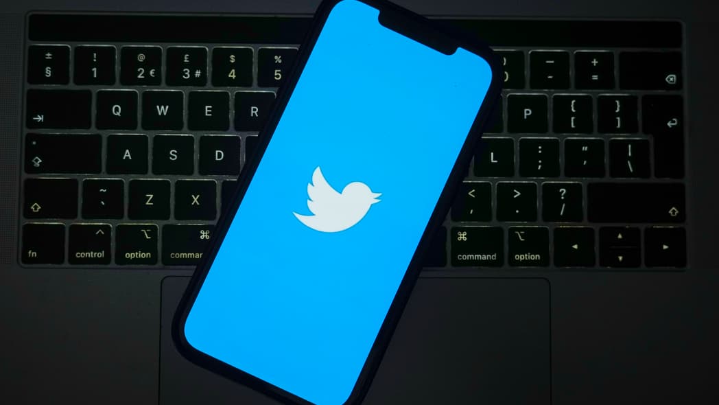 The Twitter logo on a cell phone screen over a keyboard