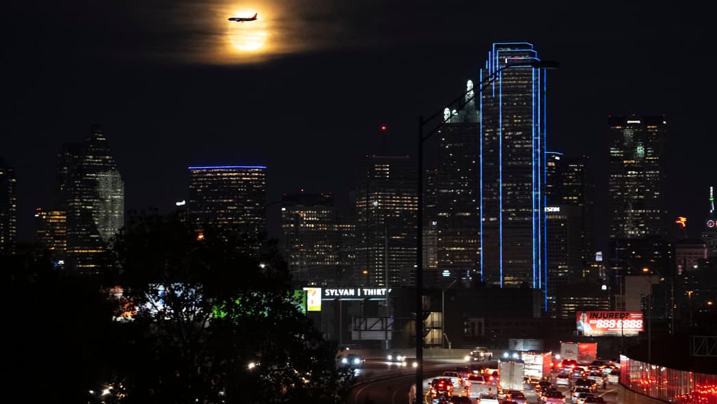 A Southwest Airlines plane makes its final approach at Dallas Love Field Airport near a the full moon