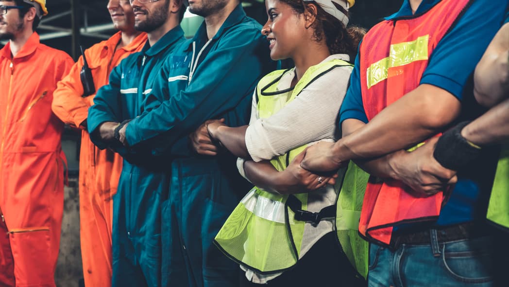 A group of workers with arms crossed holding hands