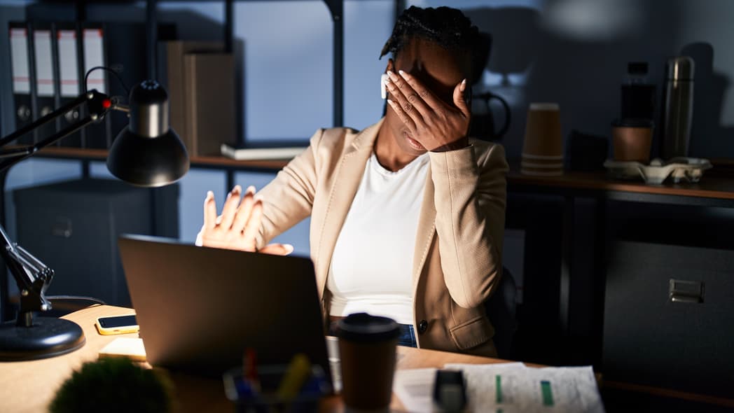 A woman covers her eyes at an image on her laptop