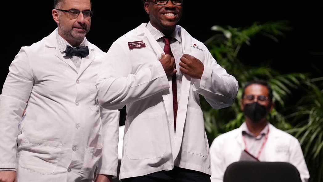 Medical student Benjamin Owens smiles as he gets his white coat from Dr. Nersi Nikakhtar