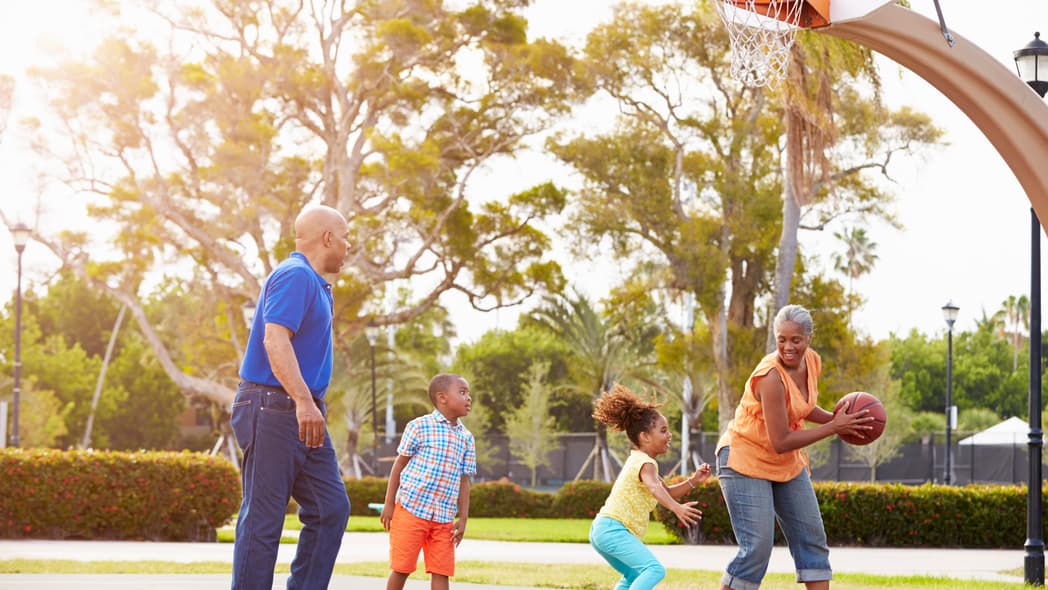 Grandparents And Grandchildren Playing Basketball Together Smiling