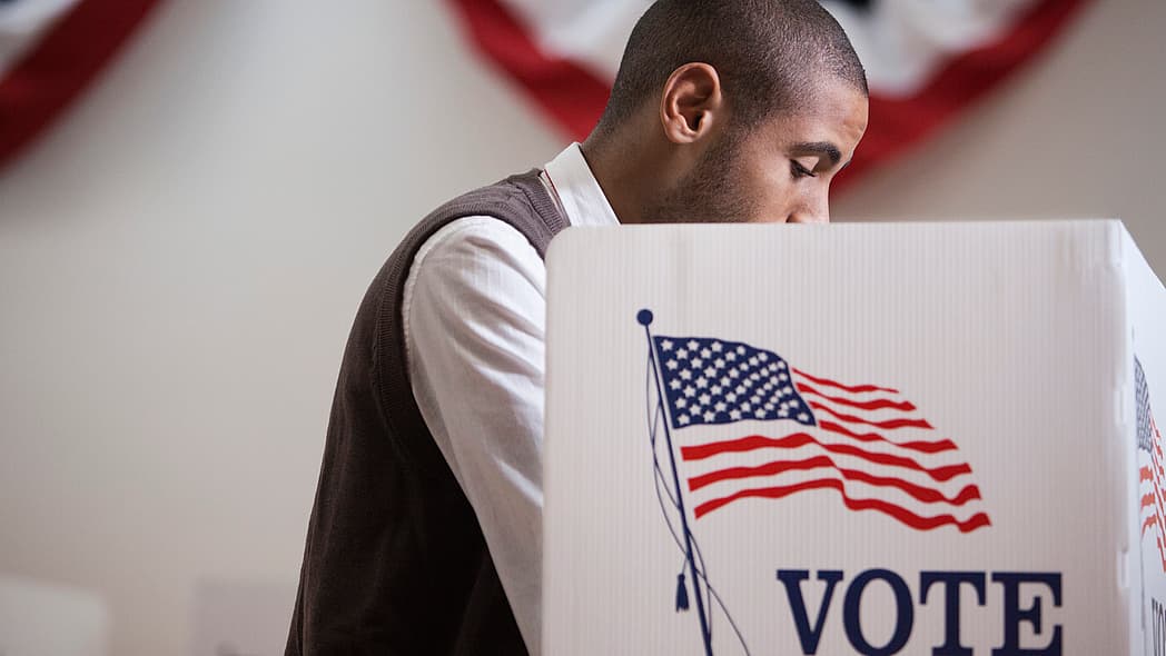 A Black male voter inside a voting booth
