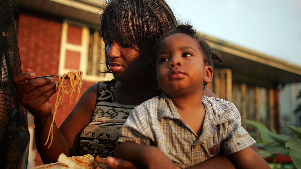 Mom feeding child food theGrio.com