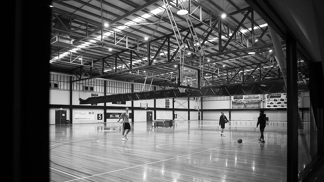 basketball court with three men practicing