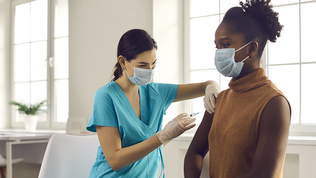 Black people health care system -- woman getting modern flu or Covid-19 vaccine at doctor's office