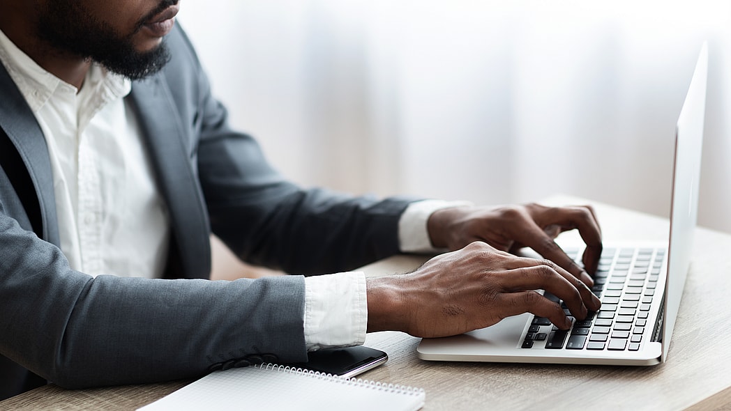 Black man in suit works on computer