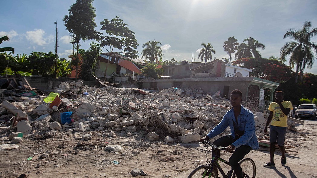 A man rides his bike by a collapsed building after a 7.2-magnitude earthquake struck Haiti