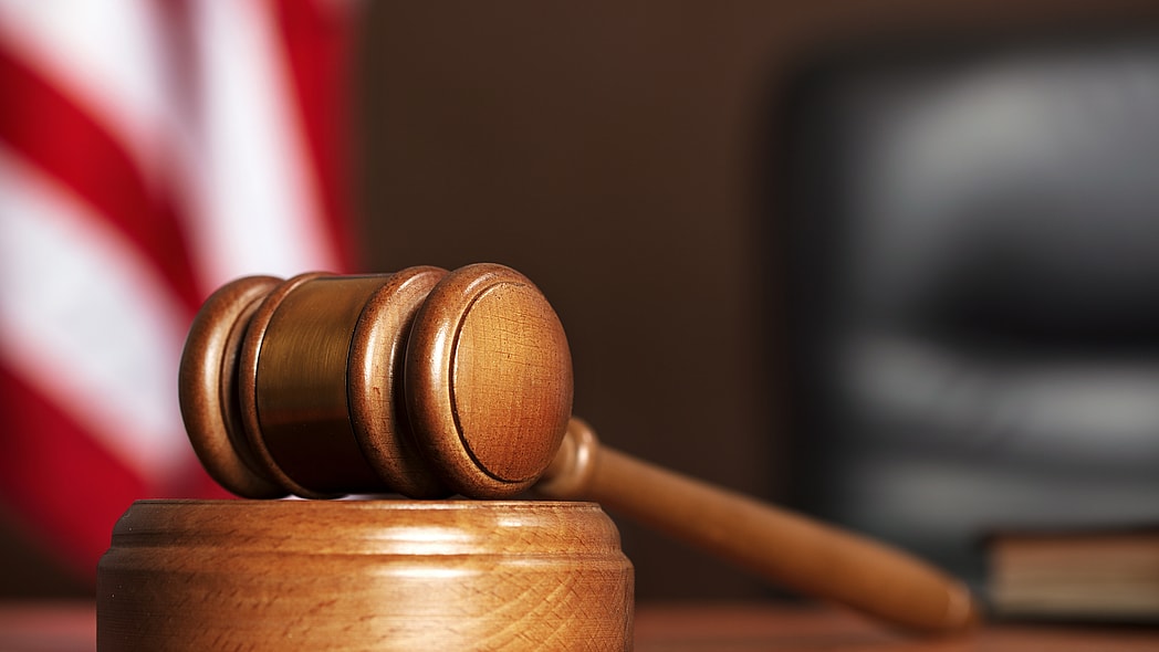 Judge Wooden gavel on the table of judge with american flag and black chair