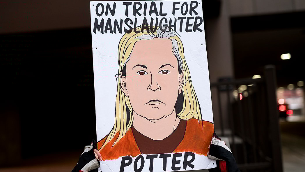 A demonstrator holds a sign with an image of Kim Potter
