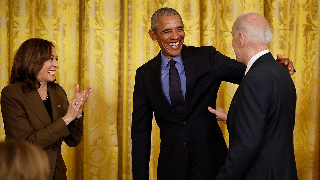 Vice President Kamala Harris applauds beside former President Barack Obama who reaches toward President Joe Biden