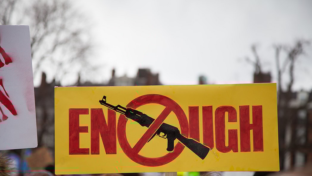 Sign reading "Enough" with an image of a gun